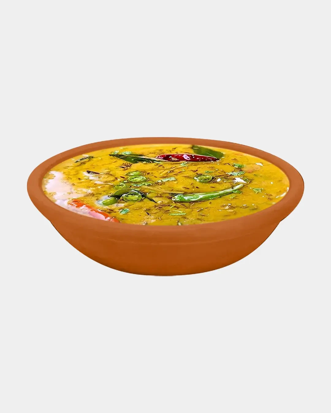 Yellow soup in a terracotta bowl on a white background