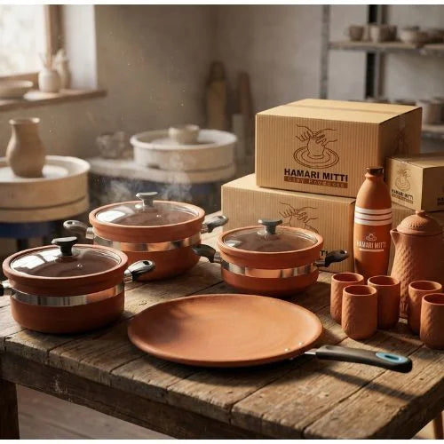Ceramic cookware set on a wooden table with 'HAMARI MITTI' branded boxes in the background.