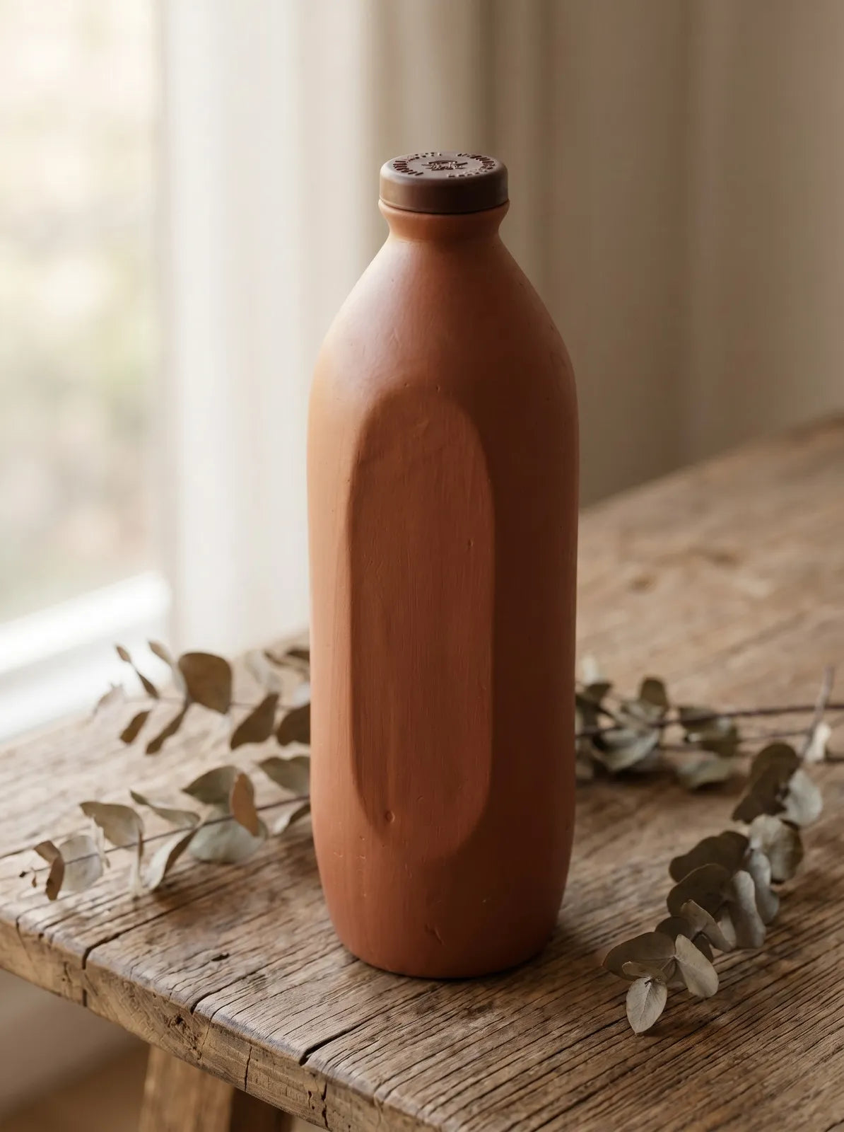 Terracotta-colored bottle on a wooden surface with a blurred background